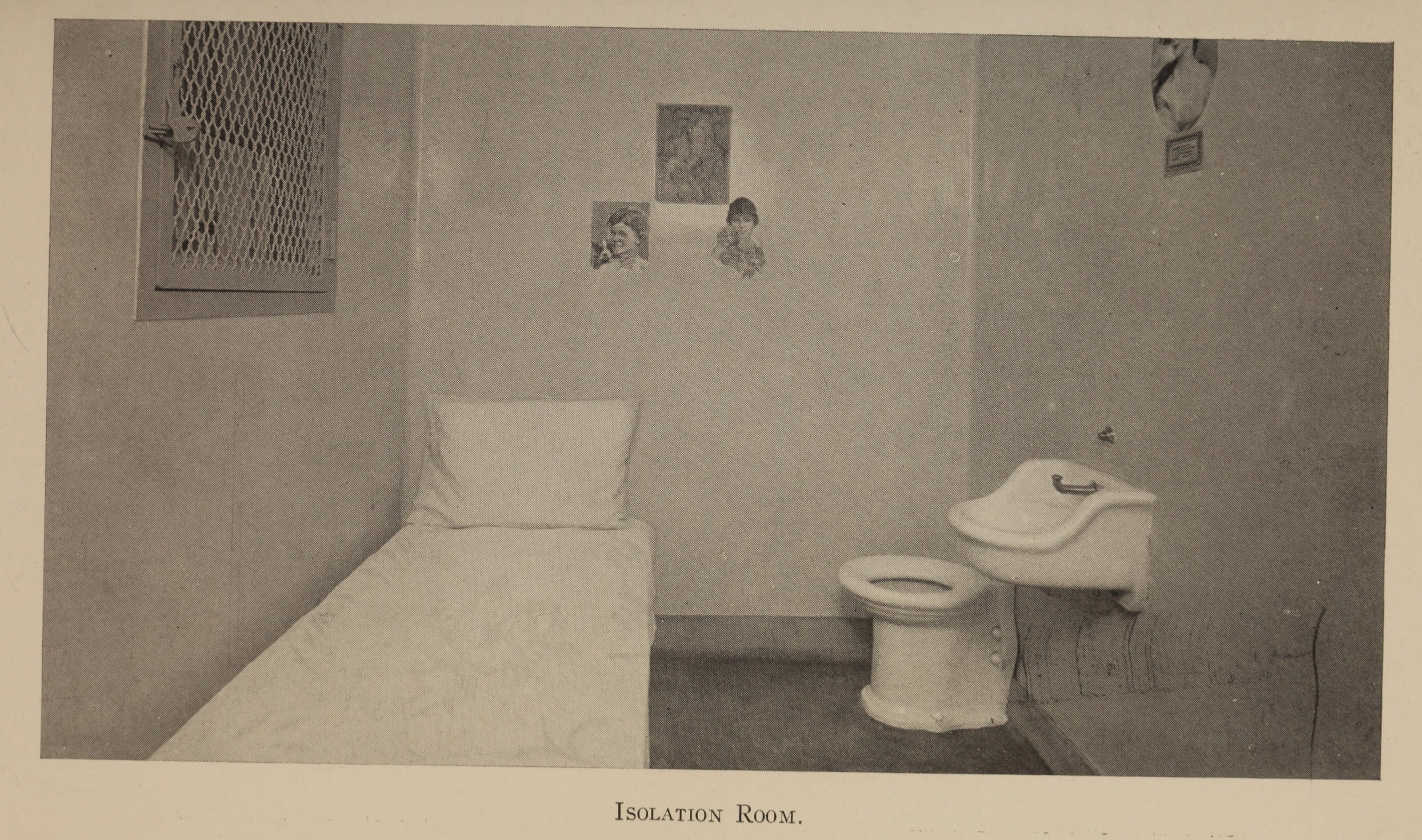 Black and white photograph of a small room with a bed, sink, and toilet