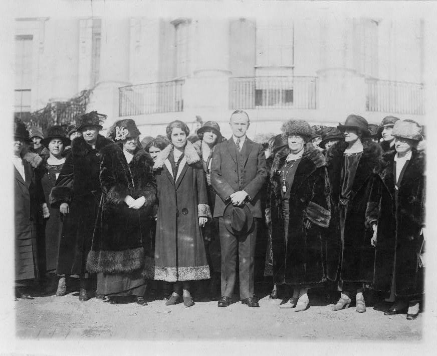 President and Mrs. Coolidge standing with group of women