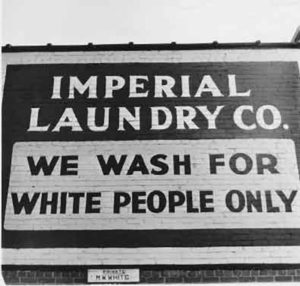 Painted sign reads: "Imperial Laundry Co. We wash for white people only"