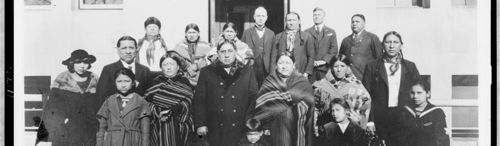 Black and white photograph of group of Osage Indians, including Franklin Revard, Chief Bacon Rind, and his wife, posed on steps, Washington, D.C.