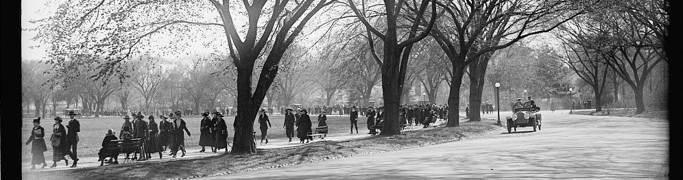 Black and white photograph of people walking around the tidal basin in Washington, DC, with trees surrounding them